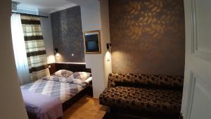 a small bedroom with two beds and a chair at Maksimilian Osijek in Osijek