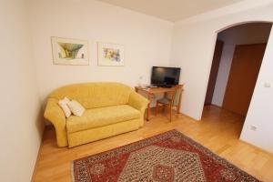 een woonkamer met een gele bank en een tafel bij Pension Christina in Weiz