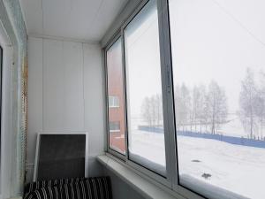 a room with a window with a chair and a snow covered yard at Апартаменты Кристалл на Пушкина 12 in Yurga