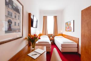 ウィーンにあるホテル アレグロ ウィーンのベッド2台とテーブルが備わるホテルルームです。