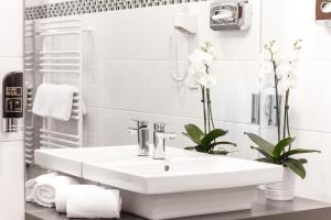 een witte badkamer met een wastafel en handdoeken bij Hotel Allegro Wien in Wenen