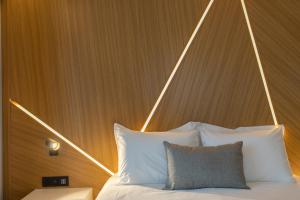 a bed with a wooden head board with white pillows at Old Port Hotel in Limassol