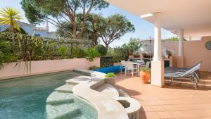 a swimming pool in a backyard with a table and chairs at Joanne in Vale do Lobo