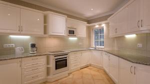 a white kitchen with white cabinets and a window at Joanne in Vale do Lobo