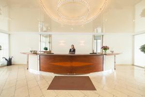 a woman sitting at a reception desk in a lobby at Novum Hotel Post Aschaffenburg in Aschaffenburg