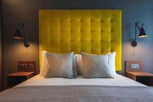 a bedroom with a large bed with a yellow headboard at The Gate London City in London