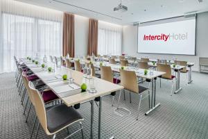 a conference room with tables and chairs and a screen at IntercityHotel Hannover Hauptbahnhof-Ost in Hannover