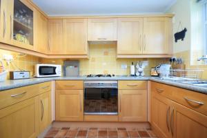 a kitchen with wooden cabinets and a stove top oven at Orchard Mews , Barnham in Barnham