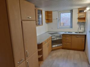 a small kitchen with wooden cabinets and a window at Zimmervermietung KaSa in Groß Lafferde