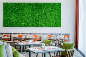 a restaurant with tables and chairs and a green wall at IntercityHotel Hannover Hauptbahnhof-Ost in Hannover