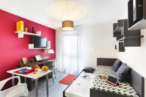 una pequeña sala de estar con una pared de acento rojo en Résidence Néméa Clermont Centre en Clermont-Ferrand