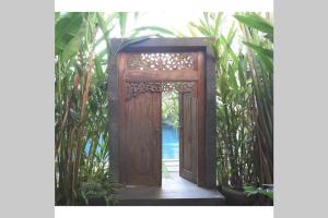 una puerta de madera abierta en un jardín con plantas en Exotic Chamber, en Malang