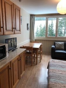 a living room with a table and a kitchen at RÉSID BEC DE L AIGLE Studio 22 - LE LIORAN in Laveissière +15 photos