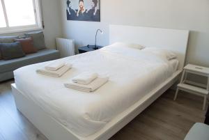 uma cama branca com toalhas num quarto em Baixa24 - Bolhão Apt with Sunset Rooftop no Porto