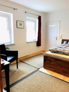 sypialnia z łóżkiem i krzesłem oraz 2 oknami w obiekcie City Apartments w mieście Osterholz-Scharmbeck