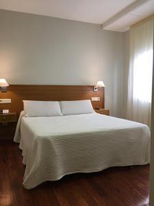 a bedroom with a white bed and a window at Hotel Arteixo in Arteixo