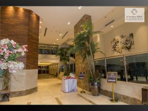 a lobby with a table and a palm tree in it at Al JAWHRA TOWER HOTEL in Mecca