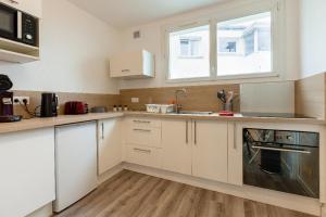 una cucina con mobili bianchi, un lavandino e una finestra di Appart Center Bara a Brest Altre 7 foto