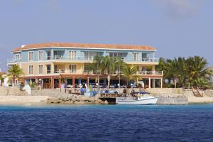 a large building on the beach with a boat in the water at Oceanfront Tarpon at Den Laman in Kralendijk +4 photos