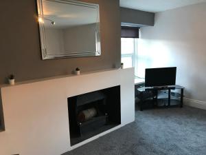 a living room with a fireplace with a mirror at The Boathouse Wylam in Wylam