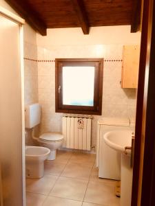 een badkamer met een toilet, een wastafel en een raam bij Il residence della salute in Montese