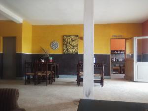 een eetkamer met gele muren en tafels en een koelkast bij Auberge Cœur Océan in Joal-Fadiout