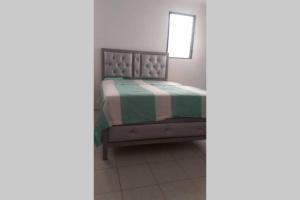 - une chambre dotée d'un lit avec une couverture verte et blanche dans l'établissement Amplio y acogedor apartamento, à Santiago de los Caballeros