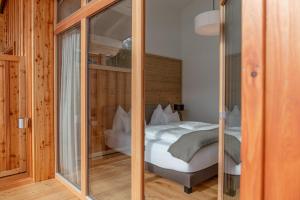 - une chambre avec un lit et un mur en verre dans l'établissement Skylodge Alpine Homes, à Haus im Ennstal