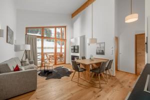 - un salon avec une table, des chaises et un canapé dans l'établissement Skylodge Alpine Homes, à Haus im Ennstal