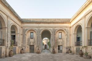 un gran edificio de piedra con arcos y un patio en Palazzo Daniele en Gagliano del Capo