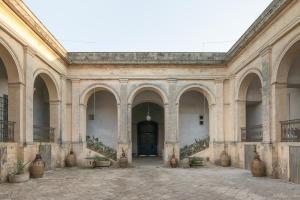 ein großes Gebäude mit einem Innenhof mit großen Vasen in der Unterkunft Palazzo Daniele in Gagliano del Capo