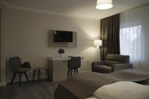 比斯平根的住宿－Hotel Bispinger Hof，酒店客房配有一张床、一把椅子和一台电视。