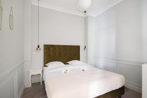 a white bedroom with a large bed with white sheets at Stylish 2bd House in Central Paris by GuestReady in Paris