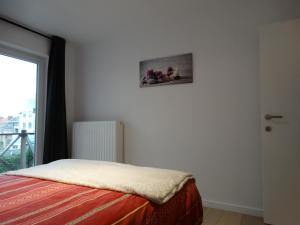 a bedroom with a bed with a picture on the wall at Appartement Ter Duinen - Lux Living in De Panne