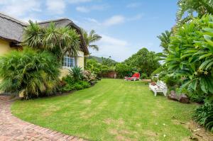 a yard of a house with a lawn and trees at Lagoon - Cottage in Wilderness