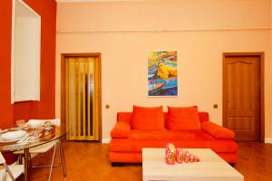 a living room with an orange couch and a table at KvartiraSvobodna - Apartment at Bolshoy Gnezdnikovskiy in Moscow