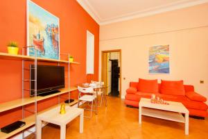 sala de estar con sofá naranja y TV en KvartiraSvobodna - Apartment at Bolshoy Gnezdnikovskiy, en Moscú