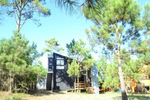 una casa negra en el bosque con árboles en El cabañon del cuervo, en Punta del Diablo