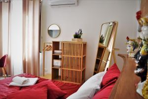 1 dormitorio con 1 cama con sábanas rojas y espejo en Le Moresche Apartment, en Catania