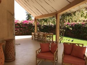 a patio with chairs and a table with pink flowers at Villa petite cote in Saly Portudal