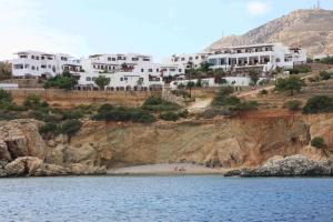 a group of white houses on a cliff next to the water at Aegean Village Beachfront Resort in Amoopi