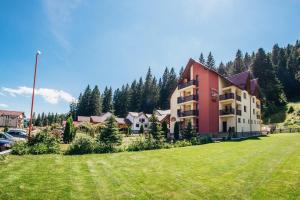 a large building on a grass field next to a parking lot at Pensiunea Sami in Gura Humorului