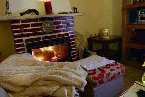 a living room with a fireplace with a blanket at LaCasitadelaPraderapuntoes in Torremocha de Jarama