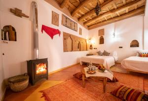 a living room with two beds and a fireplace at Dar Essalama Dades in Akhendachou nʼAït Ouffi