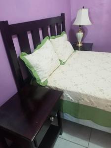 ein Schlafzimmer mit einem Bett mit einem Tisch und einer Lampe in der Unterkunft Elizabeth Enchantments in La Ceiba