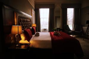a hotel room with a bed, chair, lamp and window at Culane House Hotel - B&B in Edinburgh