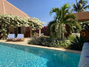 a swimming pool in front of a house with two chairs at Villa petite cote in Saly Portudal