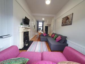ein Wohnzimmer mit lila Sofas und einem Kamin in der Unterkunft Shaftesbury Avenue Townhouse in Belfast