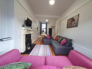 uma sala de estar com sofás roxos e uma lareira em Shaftesbury Avenue Townhouse em Belfast