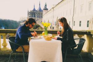 un hombre y una mujer sentados en una mesa comiendo comida en Vila U Varhanáře, en Kutná Hora